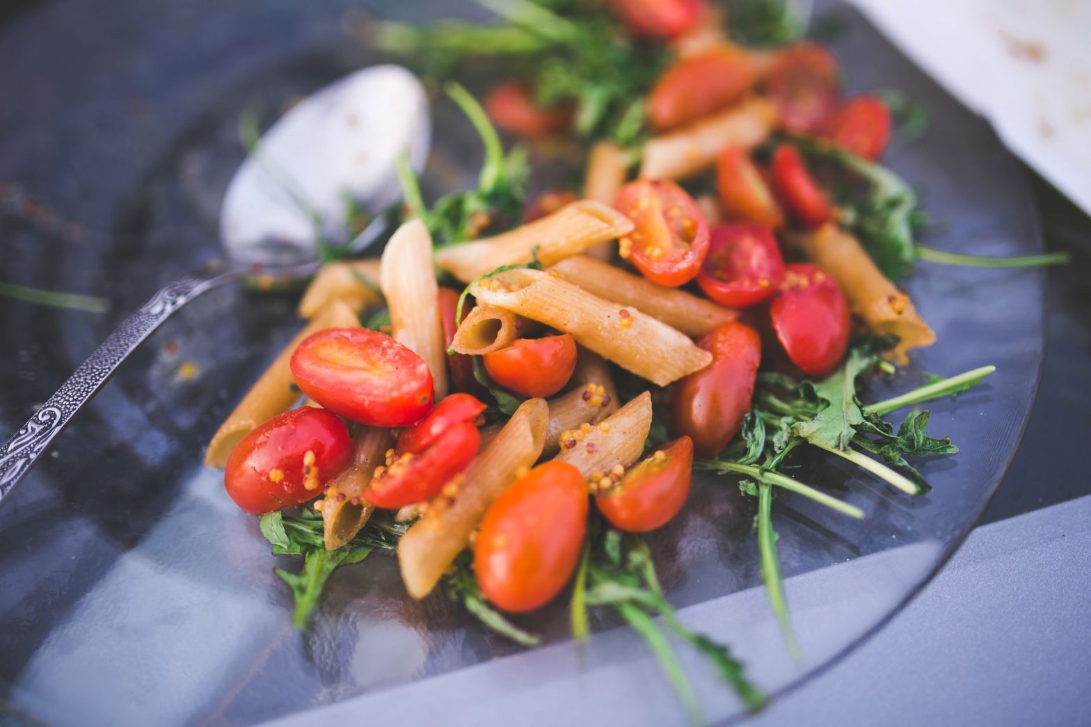 Fresh penne pasta salad with cherry tomatoes and arugula on a glass plate. — Steak Restaurant: A Go-To Destination for Meat L